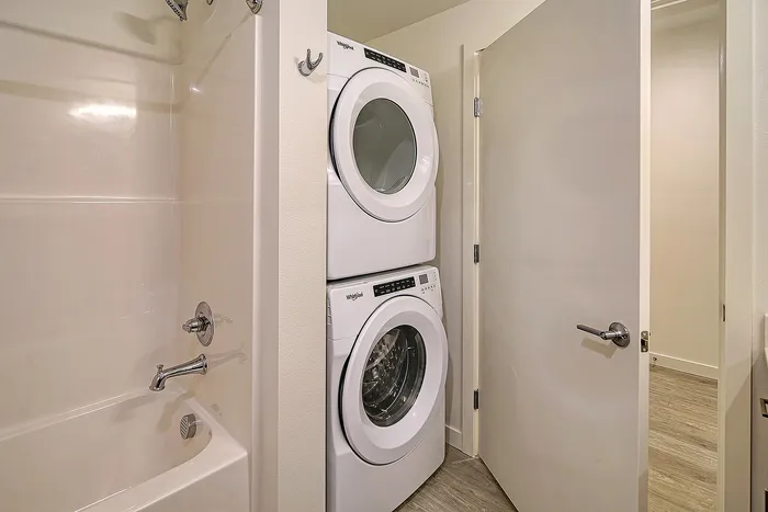 Modern bathroom featuring a sleek white bathtub and a convenient in-unit washer and dryer set.