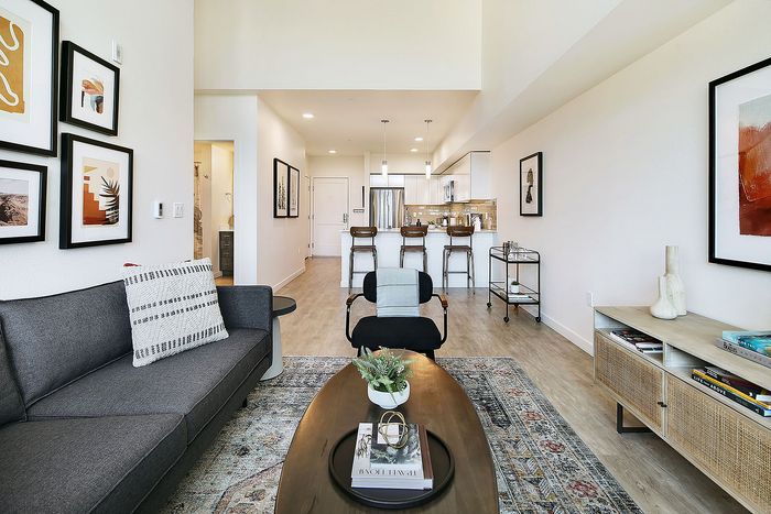 Contemporary open-plan living area with sleek kitchen and stylish decor, featuring modern furnishings and warm wood flooring.