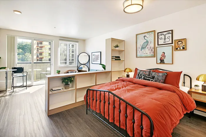 Bright, modern bedroom with a cozy red bed, stylish decor, and a sunlit balcony ideal for relaxation.