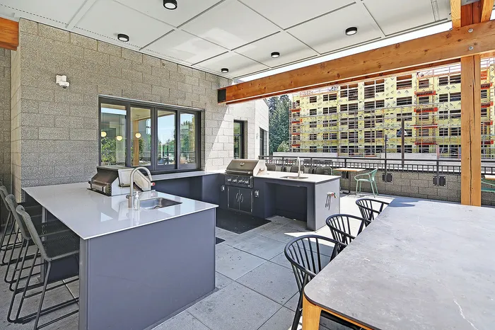Modern outdoor kitchen with sleek countertops, a built-in grill, and stylish bar seating, perfect for entertaining.