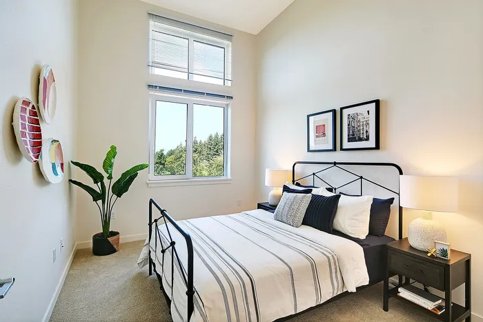 Bright and airy modern bedroom with a large window view, featuring chic decor and a cozy double bed with stylish bedding.