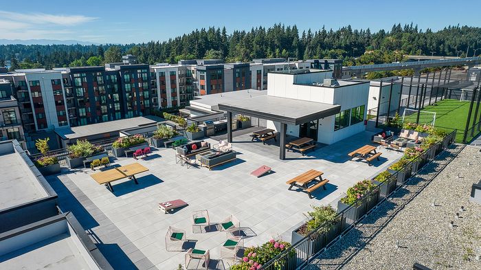 Spacious rooftop terrace featuring stylish seating areas, entertainment spaces, and lush greenery with stunning views of surrounding greenery and modern architecture.