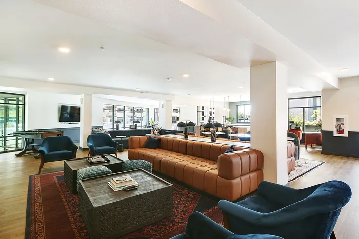 Chic communal living space showcasing modern leather sofas, rich decor, and panoramic windows for ample natural light.