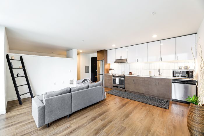 Bright, modern open-concept living space with sleek kitchen, cozy seating area, and stylish decor.