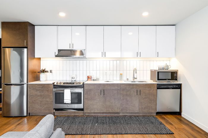 Sleek modern kitchen with stainless steel appliances, white cabinets, and hardwood flooring, perfect for culinary enthusiasts.