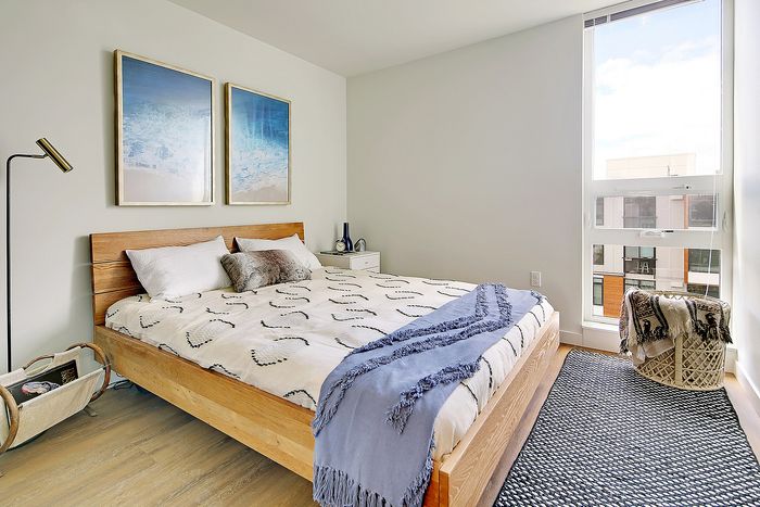 Bright, modern bedroom with a cozy wooden bed, elegant decor, and large window flooding natural light.