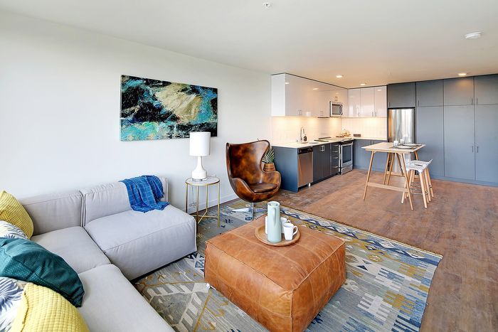Modern open-concept living area with stylish furniture, vibrant decor, and a sleek kitchen, perfect for cozy gatherings.