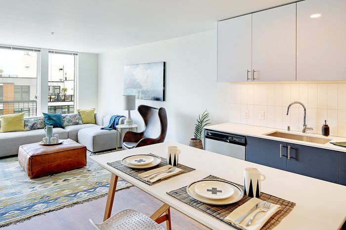 Bright and modern open-concept living space with a cozy sofa, contemporary kitchen amenities, and stylish dining setup.