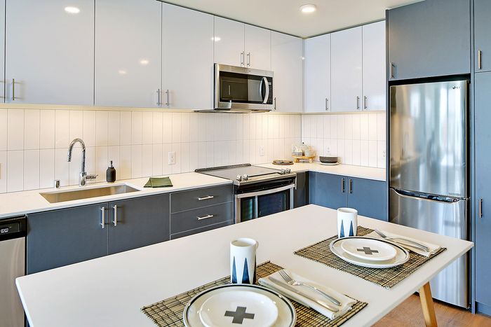 Modern kitchen design with sleek blue cabinets, stainless steel appliances, and stylish dining setup.