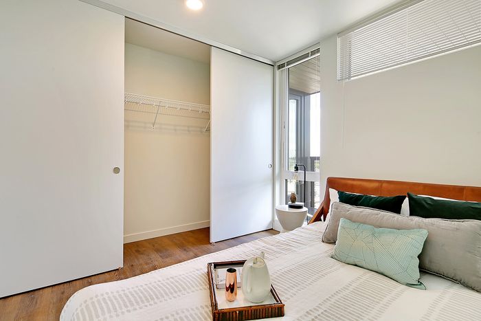 Modern bedroom with cozy bedding, spacious closet, and natural light from large windows.