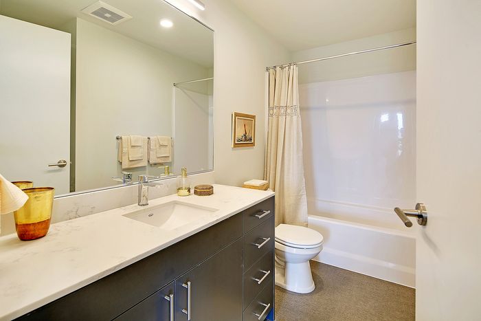 Modern bathroom with sleek dark vanity, marble countertop, and elegant decor.