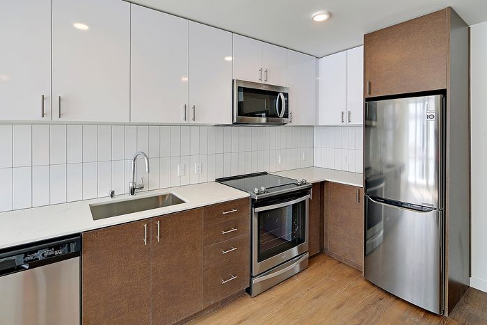 Sleek modern kitchen with stainless steel appliances, white cabinets, and chic wood accents.