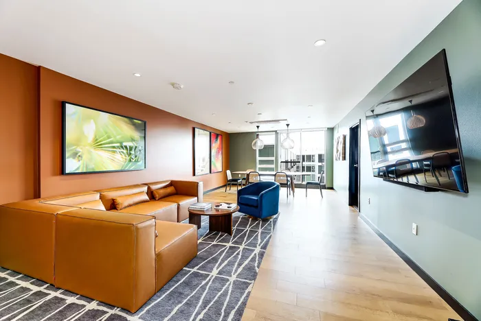 Contemporary living room with stylish leather sectional, vibrant artwork, and a spacious dining area bathed in natural light.