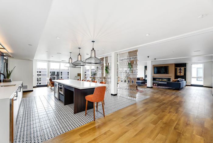 Luxurious open-concept apartment with a modern kitchen, trendy pendant lighting, and a cozy living area featuring a stylish fireplace.
