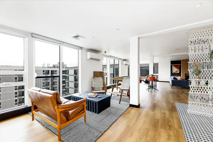 Bright and modern open-concept living area with stylish seating, panoramic city views, and elegant wooden flooring.