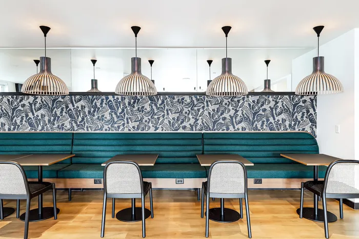 Chic dining area with elegant pendant lighting, tropical wallpaper, and modern teal seating, perfect for stylish gatherings.