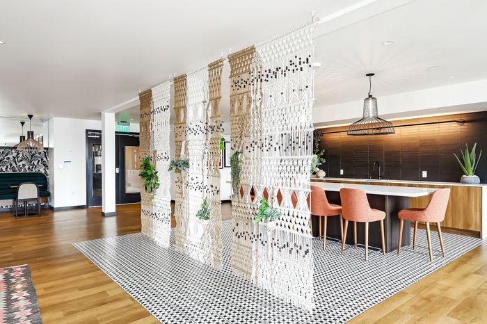 Chic and modern apartment featuring a stylish woven room divider, vibrant chairs at a sleek kitchen island, and elegant pendant lighting.