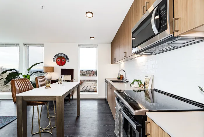 Modern kitchen and dining area with sleek appliances, white countertops, and a stylish table overlooking a scenic city view.