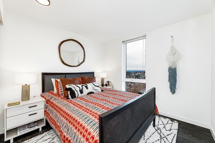 Chic bedroom with colorful bedding, modern decor, large window offering stunning scenic views, and cozy ambiance.