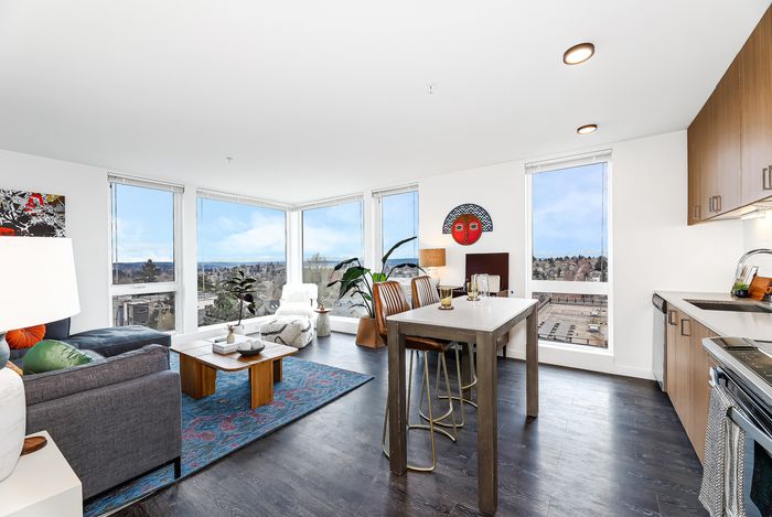 Bright, modern apartment living space with panoramic city views, stylish furnishings, and an inviting open-plan layout.