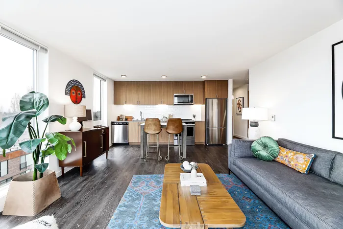 Modern open-plan living space with sleek kitchen, cozy seating, and abundant natural light from large windows.