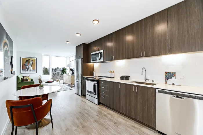 Modern kitchen and living area with sleek cabinets, stainless steel appliances, and scenic views through large windows.