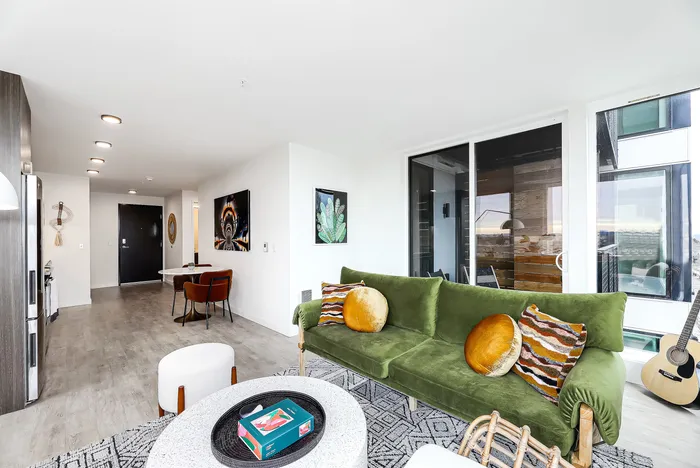 Modern apartment living room with elegant green velvet sofa, vibrant decor, and floor-to-ceiling windows offering a breathtaking view.