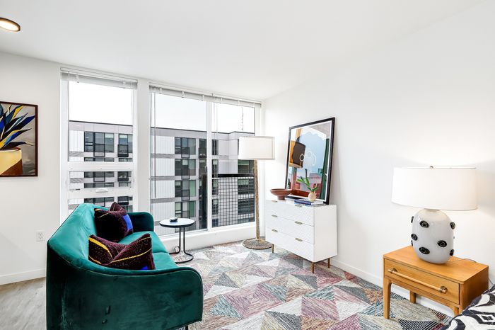 Chic apartment living area with a vibrant green sofa, modern decor, and expansive city views through large windows.