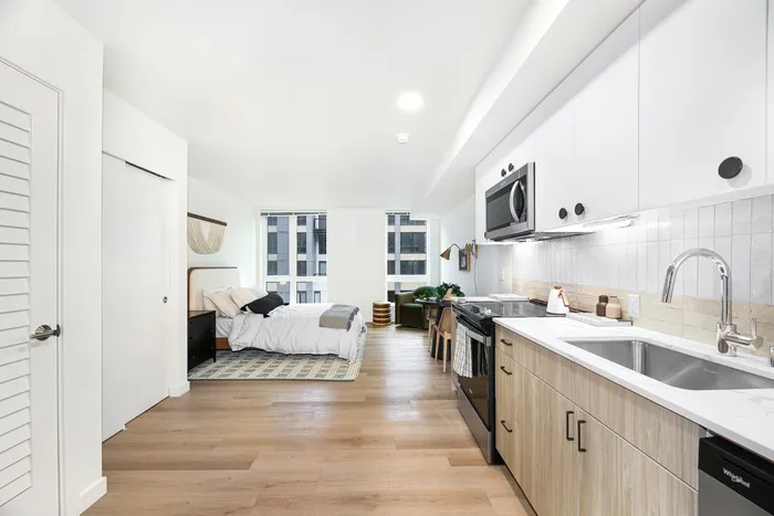 Modern studio apartment with sleek kitchen, cozy sleeping area, and abundant natural light.