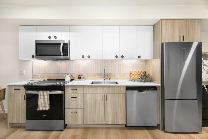 Modern kitchen with sleek appliances, bright cabinetry, and elegant wood accents, perfect for culinary creativity.