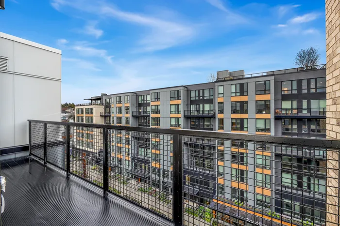 Modern apartment balcony view overlooking stylish urban architecture with vibrant facades and a clear blue sky.