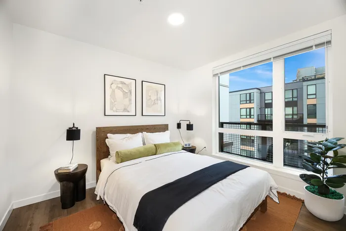 Elegant and cozy bedroom with modern decor, featuring a plush bed, stylish artwork, and a large window with urban views.