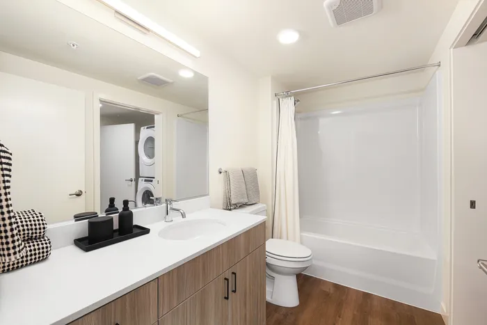 Sleek bathroom with modern fixtures, wood cabinetry, and in-unit laundry for ultimate convenience.
