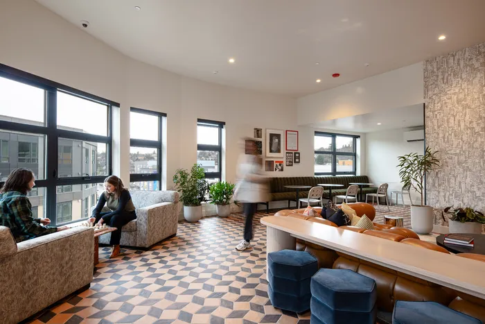 Modern and inviting lounge area with geometric flooring, stylish seating, large windows, and lush greenery.