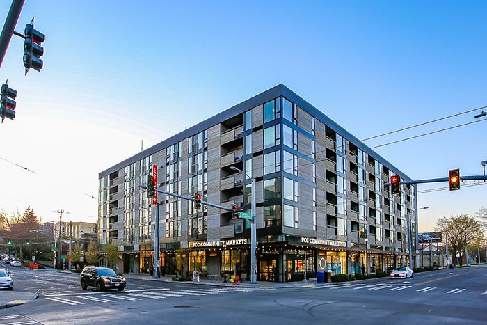 Modern urban apartment building with expansive windows, prime corner location, and street-level retail space.