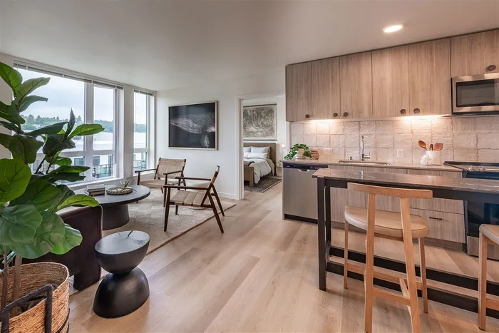 Contemporary apartment showcasing an open living area with floor-to-ceiling windows, cozy dining nook, modern kitchen, and elegant bedroom entrance.