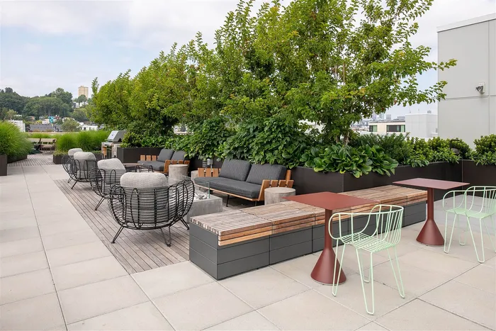 Chic rooftop terrace featuring modern seating, lush greenery, and expansive city views, perfect for relaxation and entertaining.