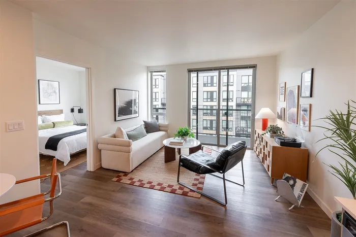 Bright and modern living room with sleek furnishings and large windows, adjacent to a cozy bedroom. A perfect blend of style and comfort in a chic apartment setting.