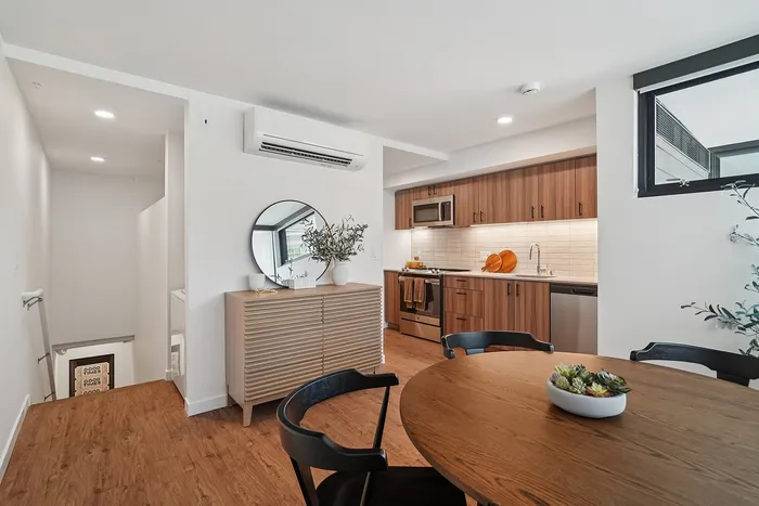 Modern kitchen and dining area with sleek wooden cabinetry, stainless steel appliances, and a chic round dining table.