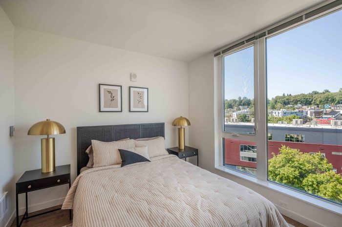 Bright and inviting bedroom with elegant decor, featuring large windows offering scenic city views and abundant natural light.
