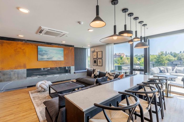 Modern living room with sleek pendant lights, large sectional sofa, and stunning floor-to-ceiling windows overlooking scenic views.