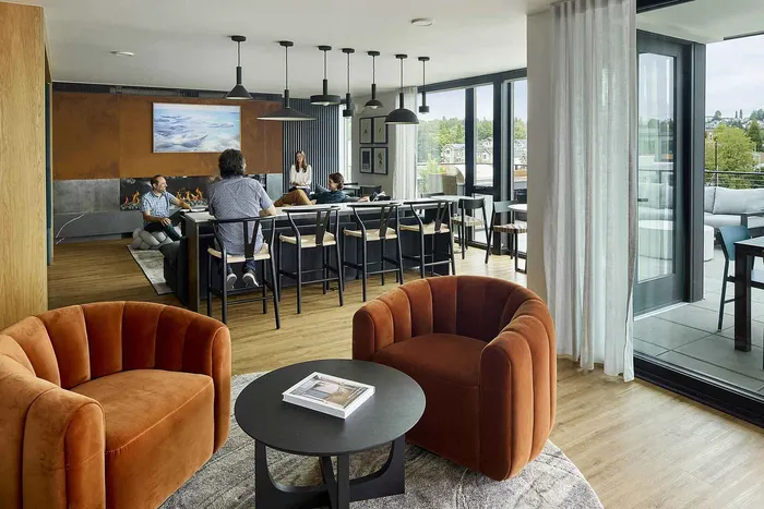 Elegant open-concept living area with modern furniture, warm lighting, and floor-to-ceiling windows offering scenic views.