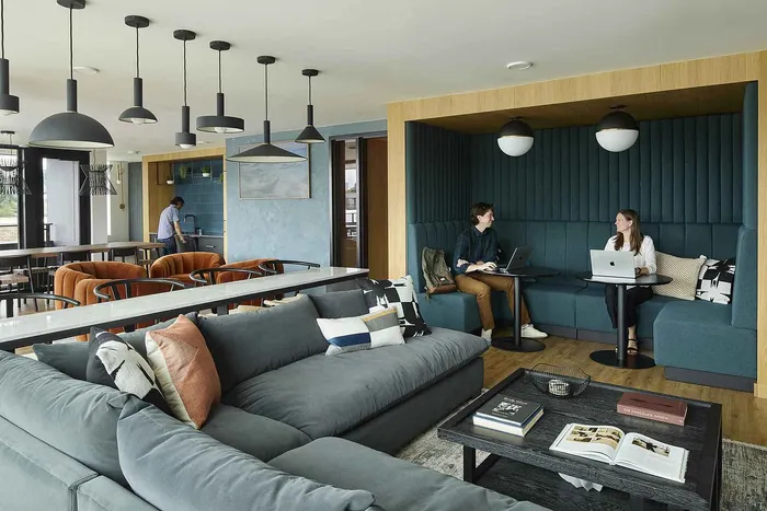 Modern apartment lounge featuring cozy seating, a stylish open kitchen, and a collaborative workspace atmosphere.
