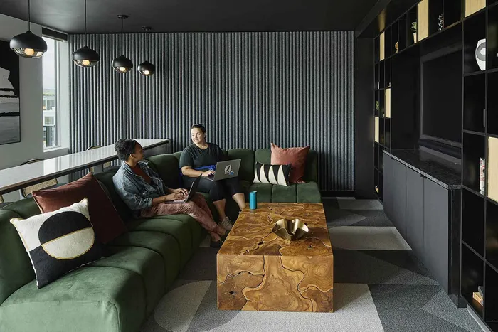 Modern living room with a cozy green sofa and stylish wooden table, featuring elegant pendant lighting and decorative pillows.
