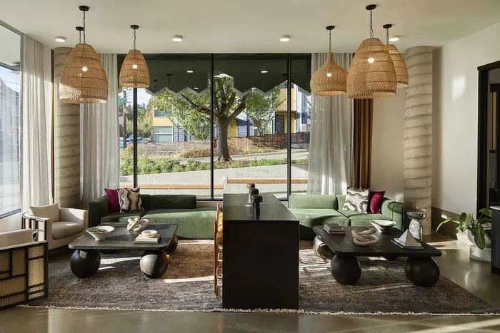 Elegant living room with large windows, green sofas, and stylish pendant lighting, offering a bright and modern space.
