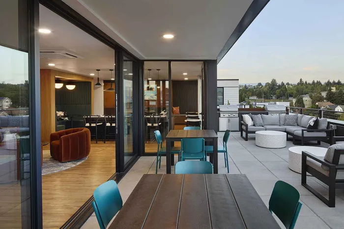 Luxurious apartment with open-plan living area leading to a spacious patio, stylish furniture, and scenic views.