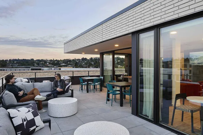 Chic rooftop terrace featuring cozy seating, modern decor, and expansive views of the surrounding landscape at sunset.