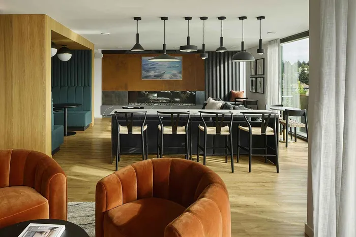 Contemporary living space with chic orange velvet chairs, stylish pendant lighting, and a cozy fireplace setting next to a dining area.