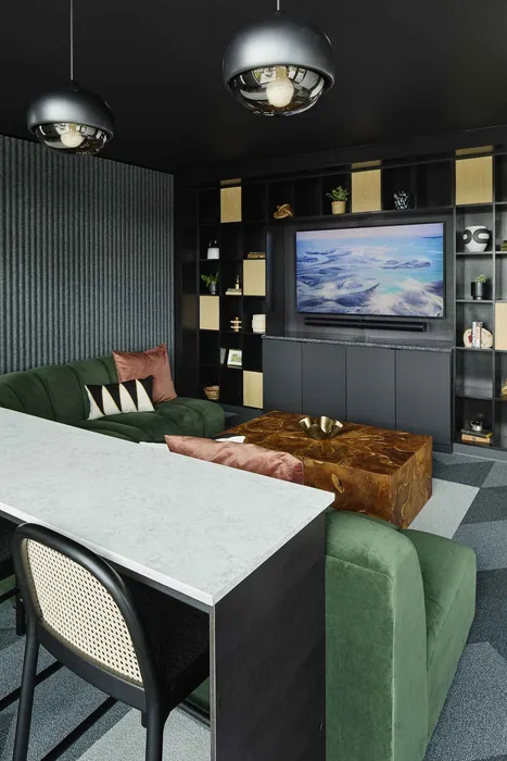 Chic and modern living room with plush green sofa, unique wooden coffee table, and stylish black shelving. Ambient lighting complements the elegant design.