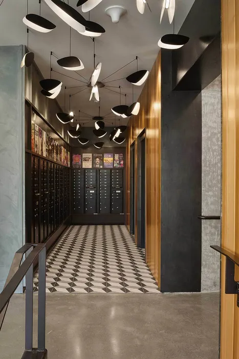 Modern hallway featuring chic, geometric flooring, artistic lighting fixtures, and sleek black mailboxes with a stylish wooden accent.